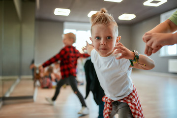 Full of energy. Cute little boy in white t-shirt looking at camera and gesturing while having a...
