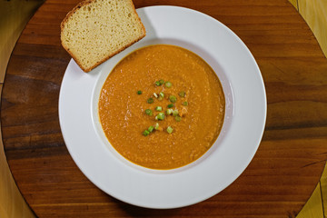 Vegetarian, gluten free peanut soup or groundnut soup in bowl with slice of gluten free bread. It...