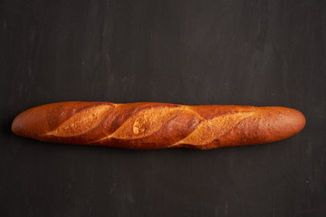 one crispy french baguettes lie on an old wooden table with free space for text