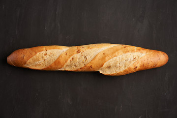 one crispy french baguettes lie on an old wooden table with free space for text
