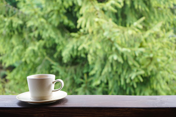 A cup of tea on the railing of the terrace, with place for text. Morning concept.  Close-up. 