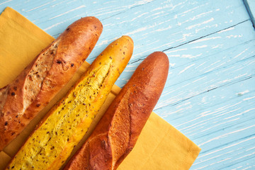 Three crispy french baguettes lie on an old wooden table with free space for text