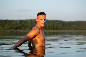 A beautiful muscular man on a lake in the water.