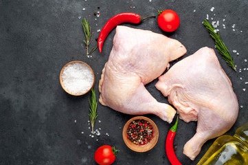 chicken legs with spices, tomatoes, sunflower oil on a stone background.