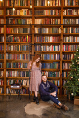 young beautiful couple sitting on the background of the library and books in the apartment in the loft style