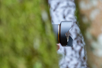 Photographer in the forest. Photographing nature and landscape. A view of the lens between the trees. Selective focus.