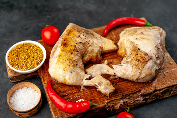 grilled chicken legs, ready to eat with spices, served on a cutting board on a stone background
