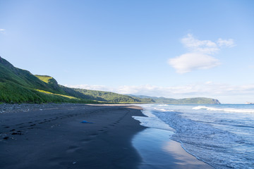 Wild beach made of volcanic sand on the Pacific Ocean, Kamchatka Peninsula, Russia.