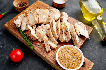grilled chicken fillet with spices, tomatoes, mustard on a stone background