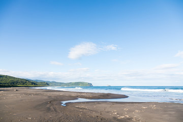 Fototapeta na wymiar Wild beach made of volcanic sand on the Pacific Ocean, Kamchatka Peninsula, Russia.