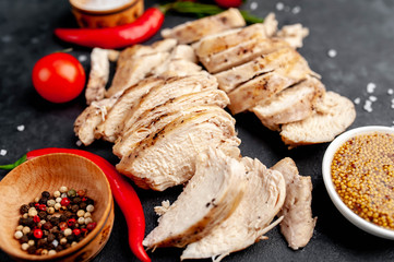 grilled chicken fillet with spices, tomatoes, mustard on a stone background