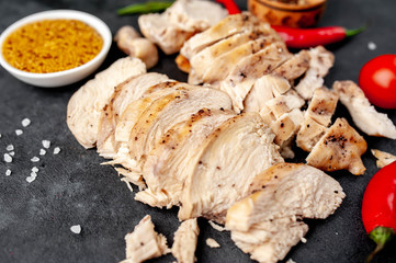 grilled chicken fillet with spices, tomatoes, mustard on a stone background