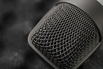 Gray studio condenser microphone on black soft foam