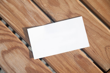 White paper card lying on wooden boards. Top view