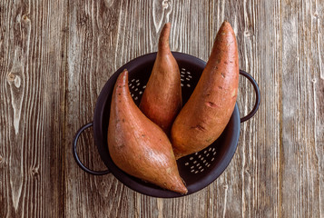 Organic farm sweet potato on rustic wooden background. Healthy eating and zero waste concept. Top...