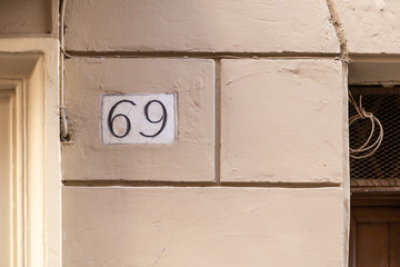 number 69, ancient house number plate on brick wall, Italy