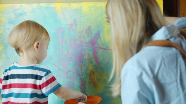  Little child making colorful draw finger on big background with mother together. 