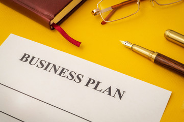 Blank form and pen for drawing up business plan on yellow table
