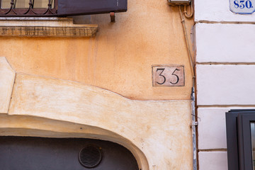 number 35, ancient house number plate on brick wall, Italy