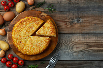 Spanish omelette with potatoes and onion, typical Spanish cuisine. Tortilla espanola. Rustic dark background. Top view with copy space