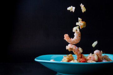Ceviche de camarón, Foto con camarones callendo al plato, camarones y verduras. 