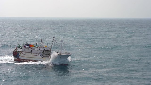 Asian fishing boat sailing on the blue waves of the ocean in sunny weather. fishing trawler sways on the waves of the Pacific Ocean. fishing industry in Taiwan 4K