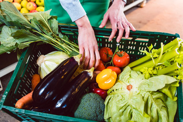 Woman working in organic supermarket putting veggies in a box