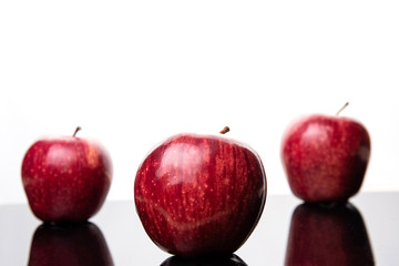 Fresh red apples placed on reflective surface