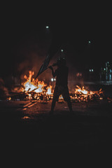  man waving night flag in protest with fire
