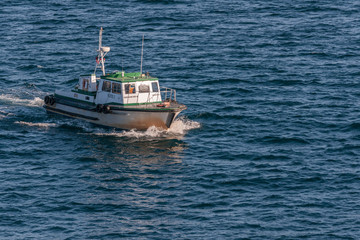 Ensenada, Mexico - January 17, 2012: Closeup of small green-white Pilot boat sailing on blue bay water.