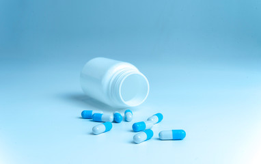 Bottle and scattered pills on color background, top view