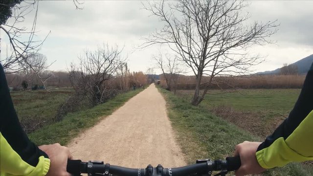 Man riding a mountain bike on a gravel path on the winter season.  Point of view footage