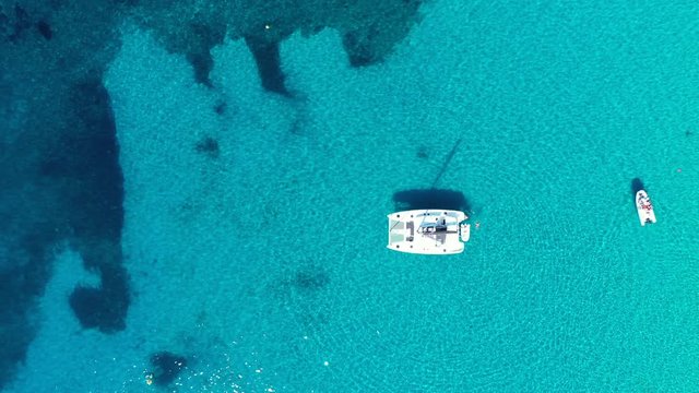 Yacht on lagoon at sunny day. Sailing boat. Yacht in the sea, aerial photography drone. Amazing yacht or sailing boat with a turquoise and transparent sea. Top view of the sailing boats in blue lagoon