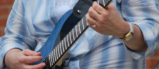 Female performing on her guitar outdoors.