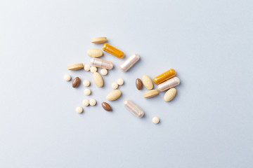 Multicolor vitamins and supplements on bright paper background. Concept for a healthy dietary supplementation. Top view. 