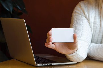 man shows a business card with mock up and copy space, works at computer. close up