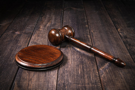 Wooden Judge's gavel on a wooden worktop, dark background. The concept of justice and dealing with court cases. Citizens' problems in courts, honesty. The work of courts and lawyers.