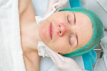 Beautician cleans face. Young woman in a beauty salon. Cosmetology concept. The cosmetologist...