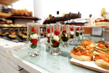 Canapes of tomatoes and cheese in a glass with pesto sauce on a blurry background