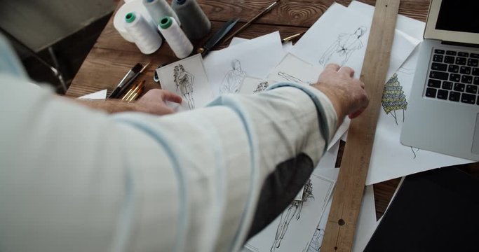 Close-up shot of hands of a clothes designer touching different beutiful sketches of new clothing collection - small business, art concept 4k footage