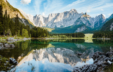 Beautiful morning scene with alpine peaks reflecting in tranquil mountain lake at sunrise