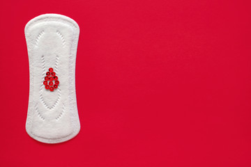 Menstrual pad with red sparkles in the form of a drop of blood on a red background, top view, miniature of the menstrual period