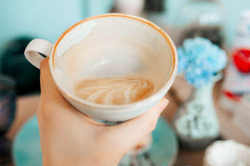 half-empty white elegant porcelain Cup with cappuccino coffee, the remnants of foam on the walls of the mug. Eating in a beautiful cafe in mint colors.