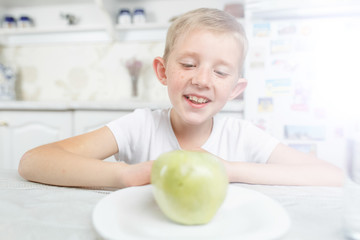 child at breakfast chooses fruit, looks at apple