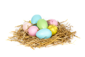 a pile of colorful large pastel easter eggs in a straw nest isolated on white