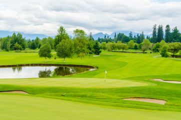 Fototapeta premium Golf course with gorgeous green and pond.