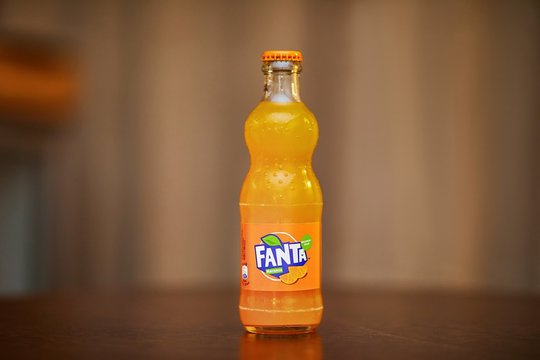 BUDAPEST, HUNGARY - CIRCA 2019: Bottle of Fanta Orange carbonated soft drink on a table, small glass bottle