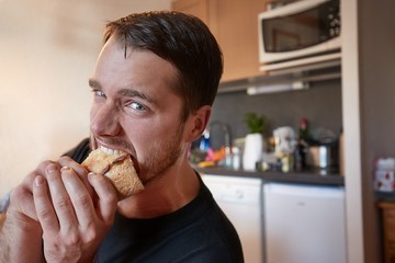Eating a sandwich biting with enthusiastic expression