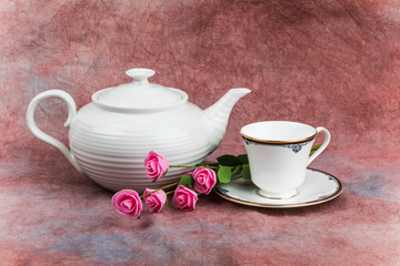 a shiny white ceramic teapot and cream and sugar set on a red fabric background