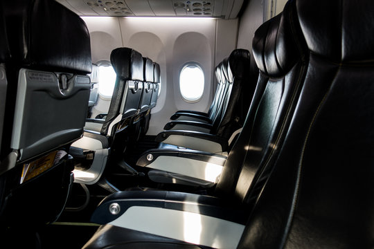 Empty passenger seats in airplane with light shining through the window.